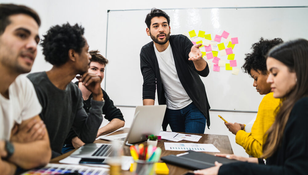 Manager leading a brainstorming meeting with a group of creative designers in the office. Leader and business concept